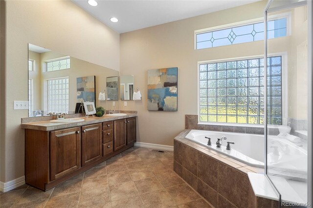 full bathroom with healthy amount of natural light, baseboards, a bath, double vanity, and a high ceiling