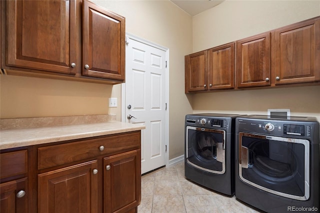 clothes washing area featuring cabinet space, washer and clothes dryer, and light tile patterned floors