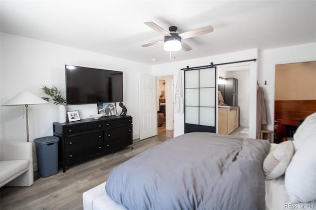 50 S Dickson St, Keenesburg, CO 80643 - bedroom featuring a barn door, light wood-type flooring, and a ceiling fan