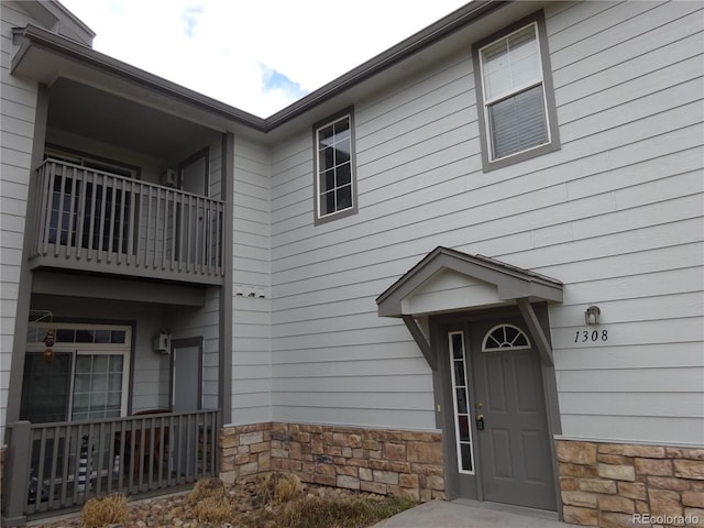 doorway to property with stone siding and a balcony