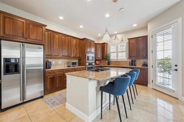 kitchen with decorative backsplash, light tile patterned flooring, a center island, light stone counters, and stainless steel appliances