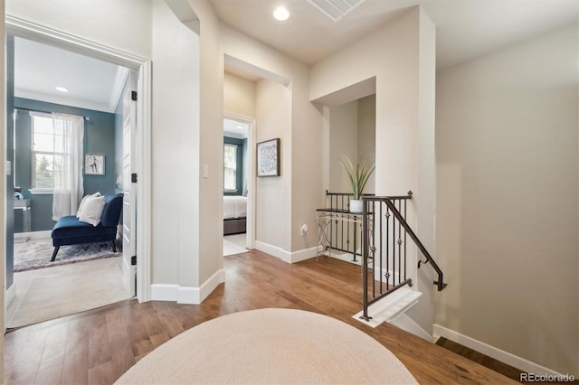 hall featuring baseboards, an upstairs landing, a wealth of natural light, and wood finished floors