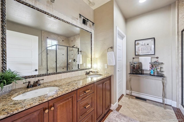 bathroom featuring a sink, baseboards, a shower stall, and double vanity
