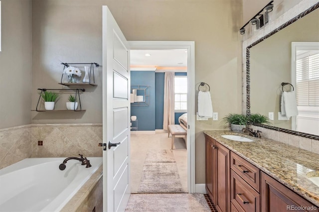bathroom with double vanity, a garden tub, ensuite bath, and a healthy amount of sunlight