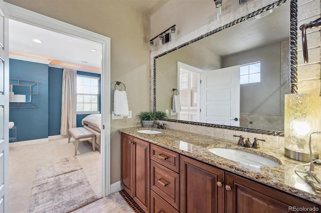 ensuite bathroom with double vanity, a sink, and a wealth of natural light