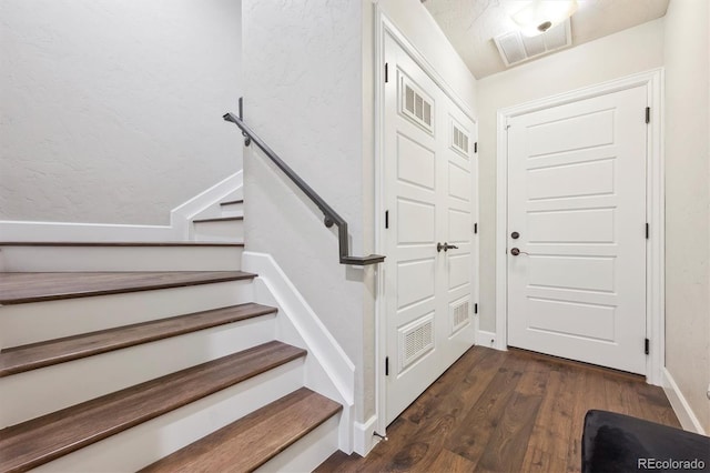 entrance foyer with stairway, baseboards, dark wood-style floors, and visible vents