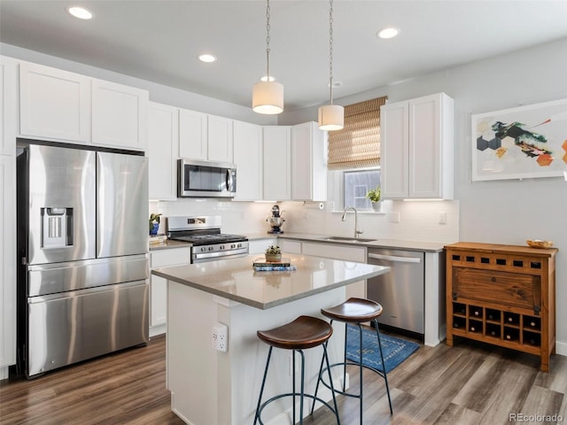 kitchen featuring dark hardwood / wood-style flooring, stainless steel appliances, a kitchen island, and white cabinetry