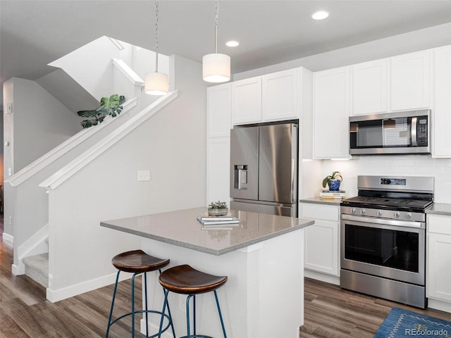 kitchen with stainless steel appliances, white cabinetry, hanging light fixtures, and dark wood-type flooring