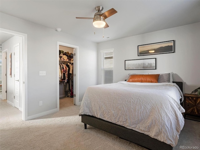 carpeted bedroom with a walk in closet, a closet, and ceiling fan