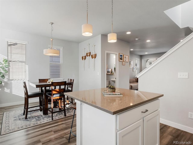 kitchen with white cabinets, dark wood-type flooring, decorative light fixtures, and a kitchen island