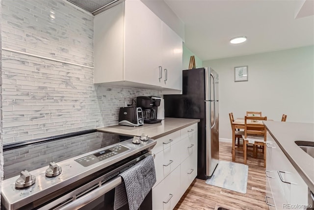 kitchen with appliances with stainless steel finishes, light countertops, white cabinetry, and backsplash