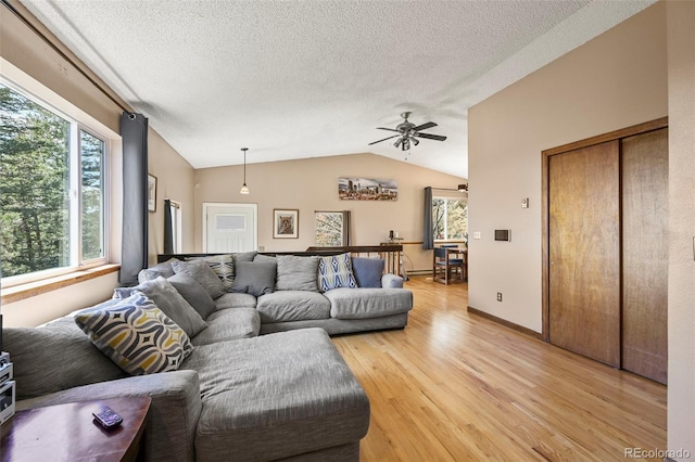 8386 S Davco Dr, Morrison, CO 80465 - living room with light wood-style floors, vaulted ceiling, a textured ceiling, a ceiling fan, and baseboards
