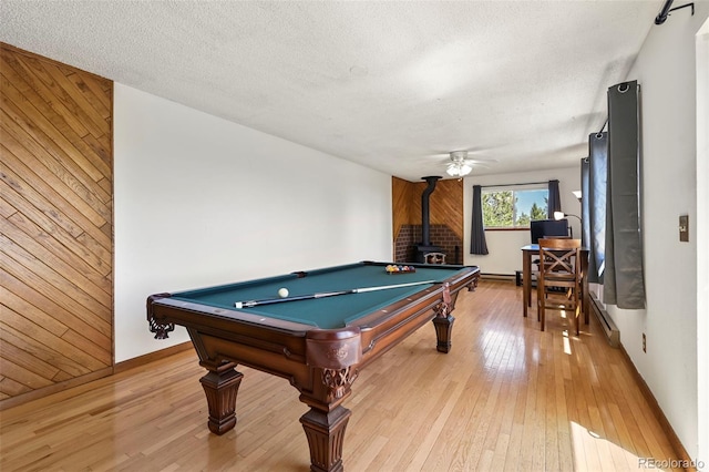 8386 S Davco Dr, Morrison, CO 80465 - rec room with a wood stove, wooden walls, light wood-style flooring, baseboard heating, and baseboards