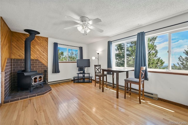 8386 S Davco Dr, Morrison, CO 80465 - sitting room featuring a wood stove, healthy amount of natural light, a textured ceiling, wood-type flooring, and ceiling fan