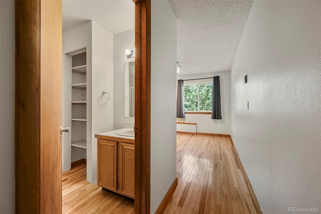 8386 S Davco Dr, Morrison, CO 80465 - hall featuring light wood-style floors, baseboards, a textured ceiling, and a sink