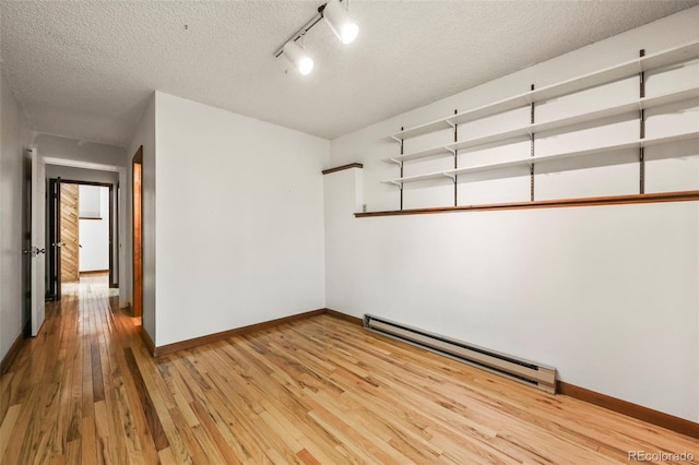 8386 S Davco Dr, Morrison, CO 80465 - spare room featuring a baseboard heating unit, light wood finished floors, baseboards, a textured ceiling, and track lighting