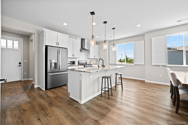1925 Peregrine Dr, Brighton, CO 80601 - kitchen featuring stainless steel appliances, wall chimney range hood, a kitchen breakfast bar, white cabinetry, and dark wood-style flooring