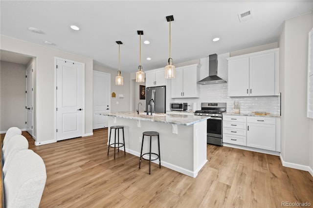 1925 Peregrine Dr, Brighton, CO 80601 - kitchen featuring wall chimney exhaust hood, appliances with stainless steel finishes, a kitchen breakfast bar, white cabinetry, and recessed lighting