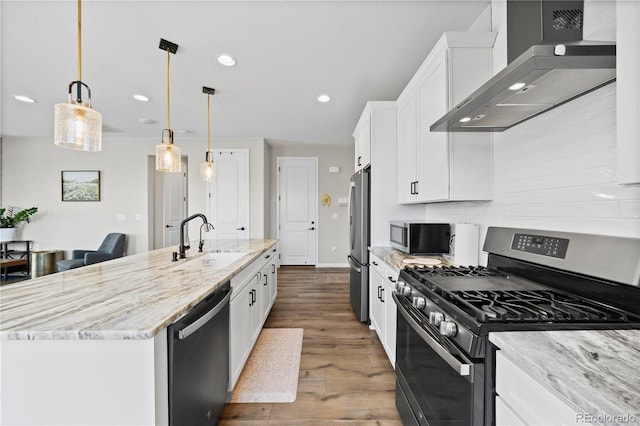 1925 Peregrine Dr, Brighton, CO 80601 - kitchen with appliances with stainless steel finishes, wall chimney range hood, white cabinets, a large island with sink, and dark wood-type flooring