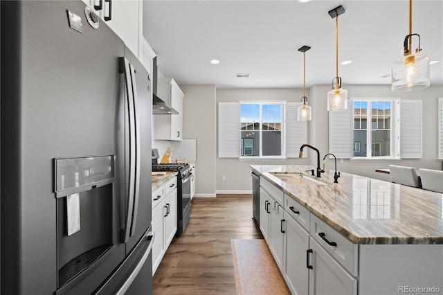 1925 Peregrine Dr, Brighton, CO 80601 - kitchen featuring stainless steel appliances, dark wood-style floors, an island with sink, wall chimney range hood, and white cabinets