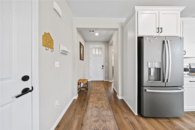 1925 Peregrine Dr, Brighton, CO 80601 - kitchen with stainless steel fridge with ice dispenser, wood finished floors, white cabinetry, and light countertops