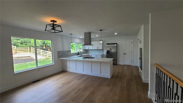 10297 W Crestone Mtn, Littleton, CO 80127 - kitchen with island range hood, stainless steel refrigerator with ice dispenser, a peninsula, a sink, and wood finished floors