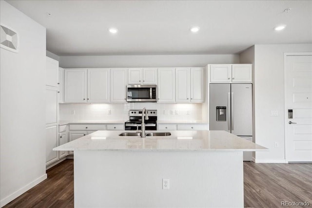 kitchen with a sink, stainless steel appliances, baseboards, light stone countertops, and dark wood-style floors