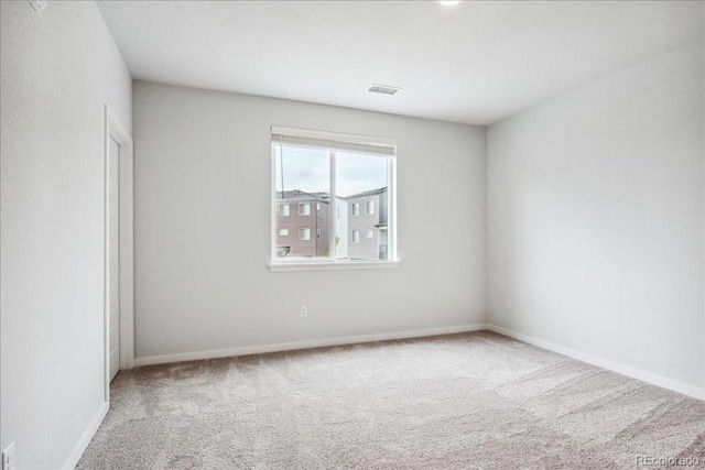 carpeted spare room featuring visible vents and baseboards