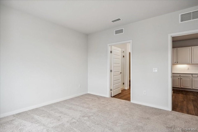 unfurnished bedroom featuring visible vents, baseboards, and dark colored carpet