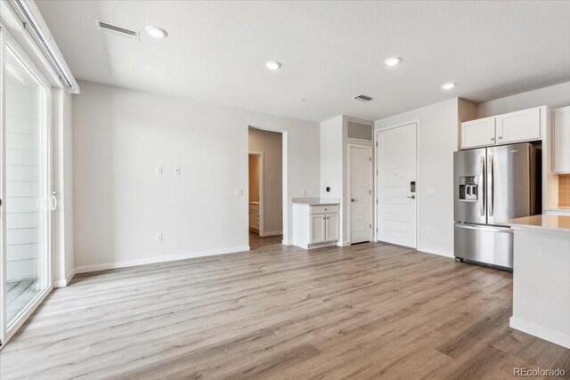 485 Interlocken Blvd Unit 209, Broomfield, CO 80021 - kitchen with stainless steel fridge, white cabinets, light countertops, light wood-style floors, and recessed lighting