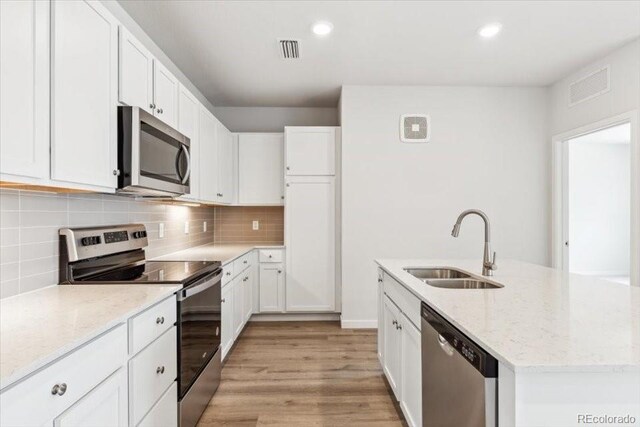485 Interlocken Blvd Unit 209, Broomfield, CO 80021 - kitchen with stainless steel appliances, a sink, white cabinets, tasteful backsplash, and recessed lighting
