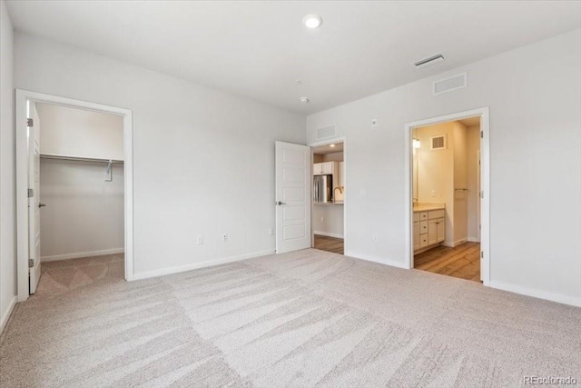 485 Interlocken Blvd Unit 209, Broomfield, CO 80021 - unfurnished bedroom featuring light colored carpet, baseboards, a spacious closet, connected bathroom, and recessed lighting