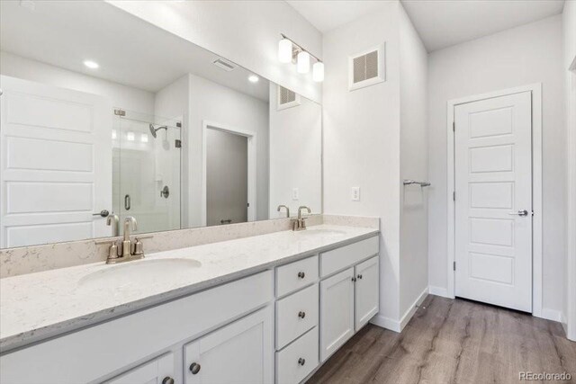 485 Interlocken Blvd Unit 209, Broomfield, CO 80021 - bathroom with double vanity, a stall shower, wood finished floors, baseboards, and recessed lighting
