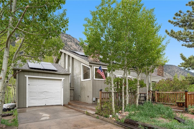 1777 Main St, Georgetown, CO 80444 - view of front of property with a shingled roof, solar panels, an attached garage, driveway, and a deck with mountain view
