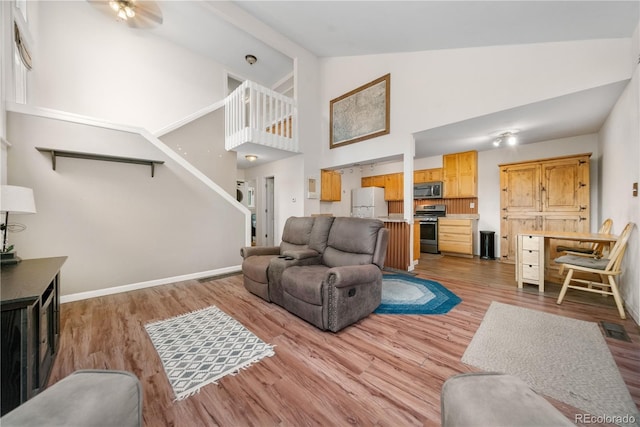 1777 Main St, Georgetown, CO 80444 - living area featuring high vaulted ceiling, light wood-type flooring, ceiling fan, baseboards, and stairway