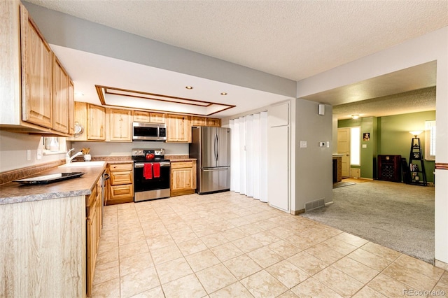 12632 W Virginia Ave, Lakewood, CO 80228 - kitchen featuring appliances with stainless steel finishes, light colored carpet, a textured ceiling, light tile patterned floors, and light brown cabinets