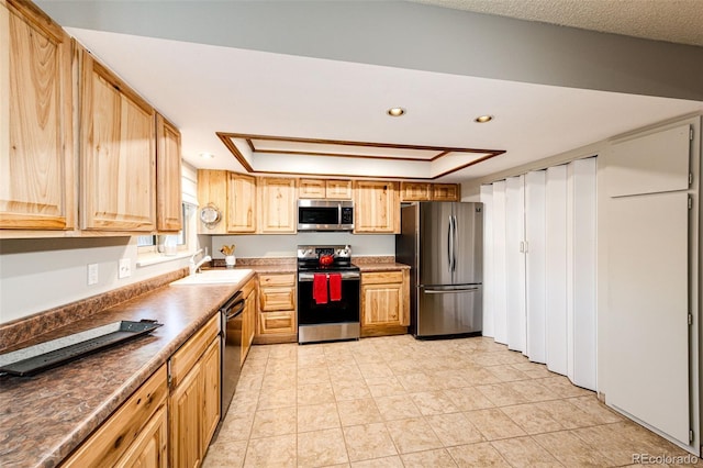 12632 W Virginia Ave, Lakewood, CO 80228 - kitchen featuring stainless steel appliances, a sink, a raised ceiling, dark countertops, and light tile patterned floors