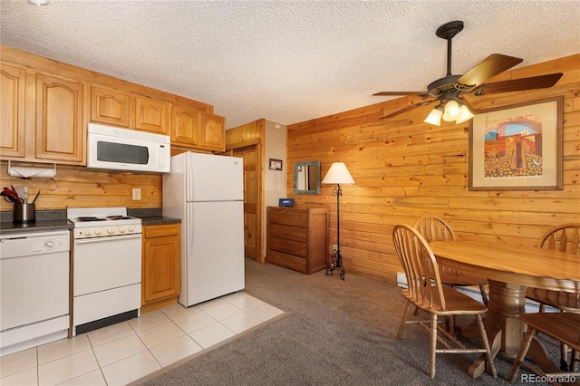 kitchen with white appliances, dark countertops, and wooden walls