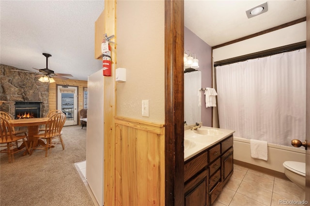 full bath featuring a fireplace, toilet, a sink, a textured ceiling, and ceiling fan