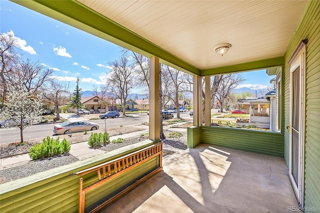 view of patio / terrace featuring covered porch, a mountain view, and a residential view