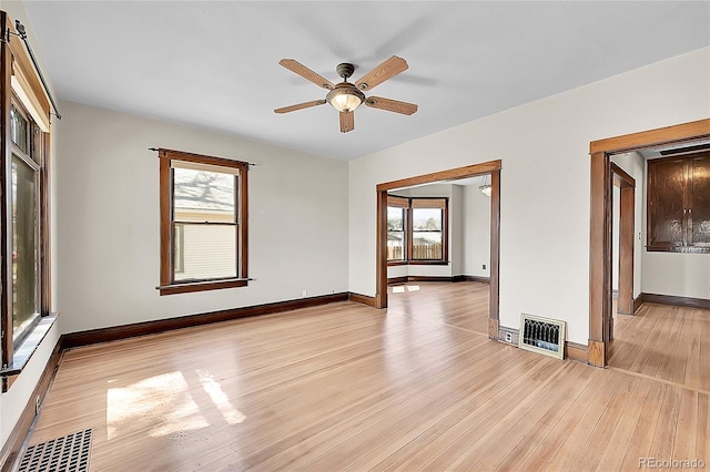 spare room featuring baseboards, visible vents, light wood-style floors, and ceiling fan