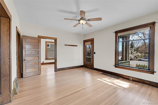 spare room featuring baseboards, a ceiling fan, visible vents, and light wood-type flooring