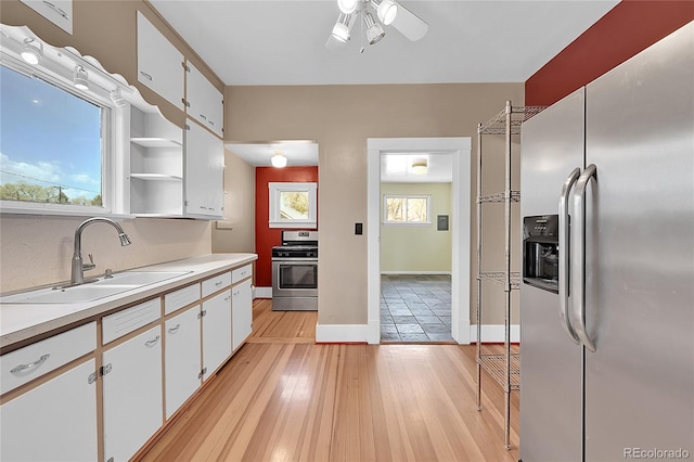 kitchen featuring white cabinets, light countertops, a sink, appliances with stainless steel finishes, and ceiling fan