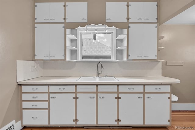 kitchen with open shelves, light countertops, white cabinets, and a sink