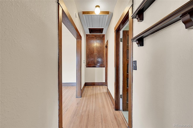 corridor with light wood finished floors and baseboards