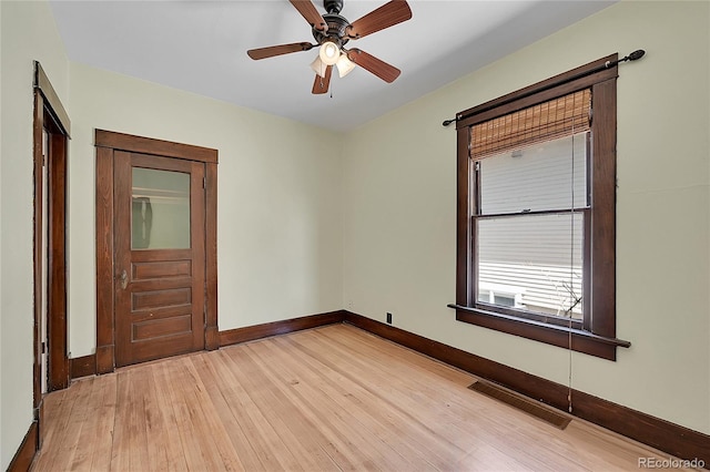 empty room featuring light wood-style floors, visible vents, baseboards, and ceiling fan