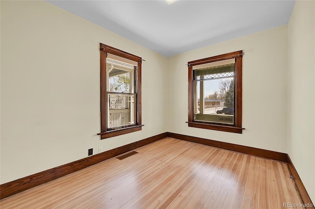 spare room featuring baseboards, visible vents, and light wood-style floors