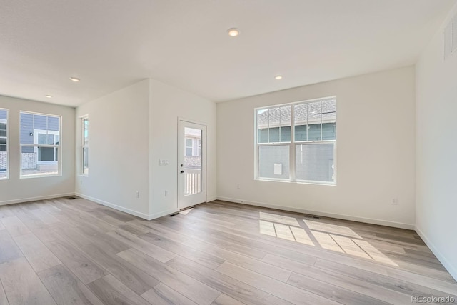 spare room featuring light hardwood / wood-style flooring and a healthy amount of sunlight