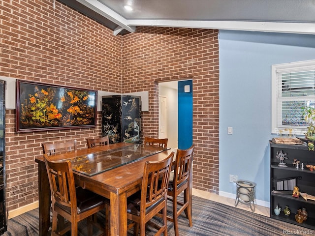 dining area with brick wall and lofted ceiling with beams