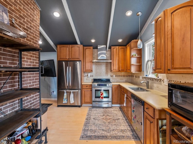 kitchen featuring light wood-type flooring, stainless steel appliances, sink, wall chimney range hood, and pendant lighting